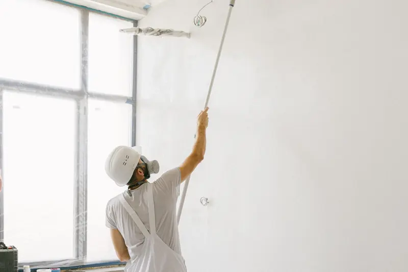 Interior painting in Fremont: professional painter in whites rolling paint onto a wall